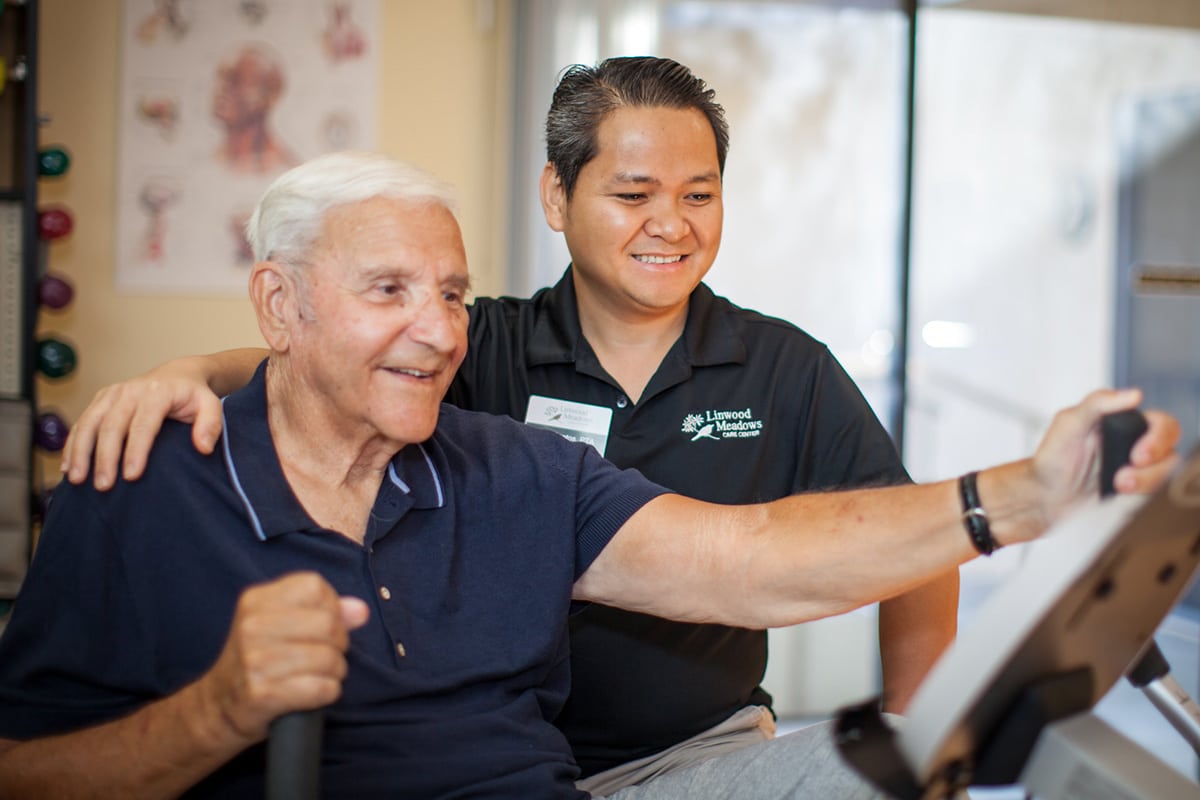 Rehab therapist working with a resident in the gym