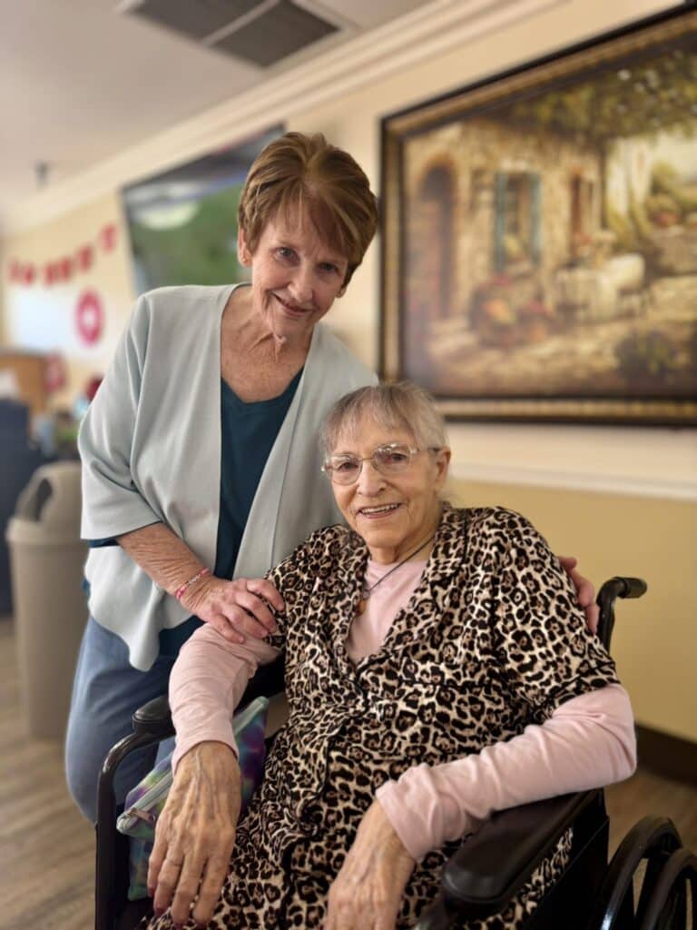 standing woman smiling with elderly woman in wheel chair at linwood meadows care facility